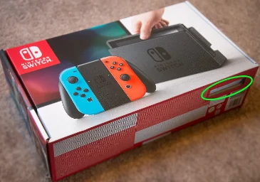 A Nintendo Switch retail box with the serial number sticker circled, visible through a cut-out window.