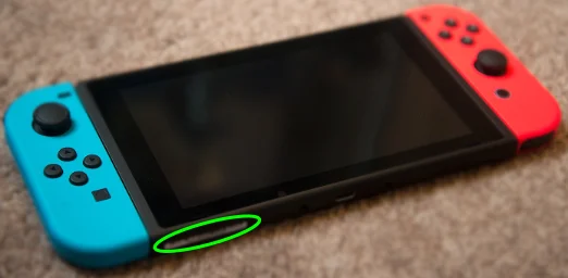 The bottom of an unboxed Nintendo Switch with the serial number sticker circled, next to the USB-C port.